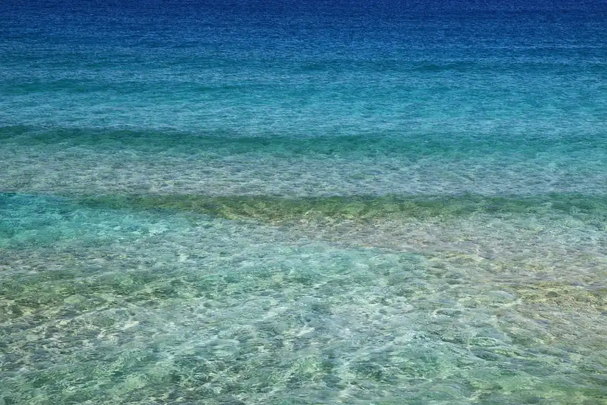 Agua clara y transparente de color turquesa con reflejos de luz del sol