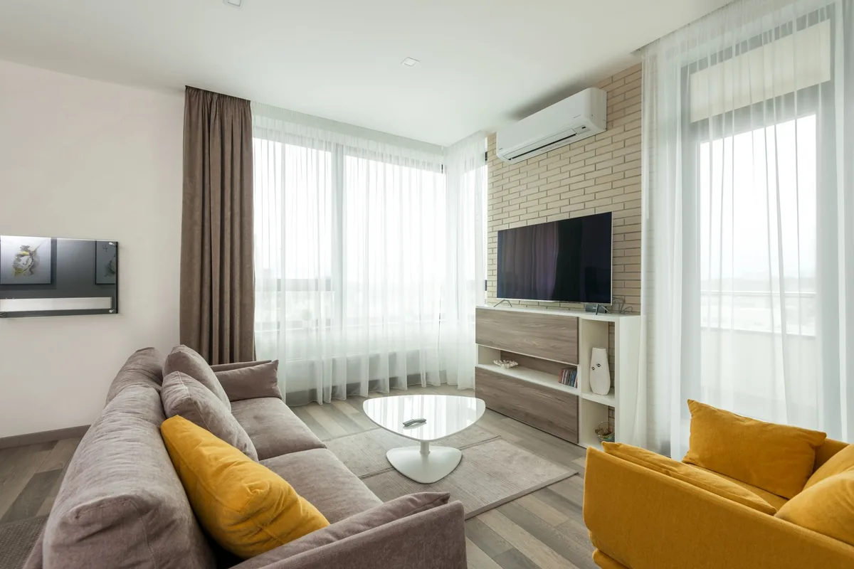 Salón con un split de pared encima de la televisión, junto a un ventanal