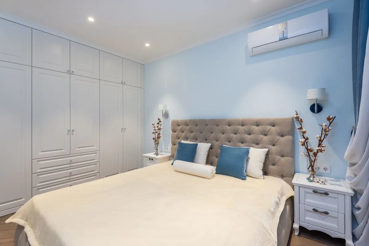 Dormitorio con un split en la pared, por encima de la cama