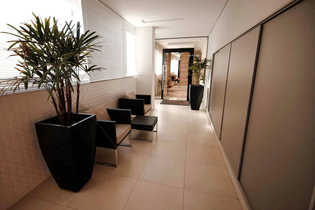 Recibidor de un local con sillones, plantas y puerta de cristal