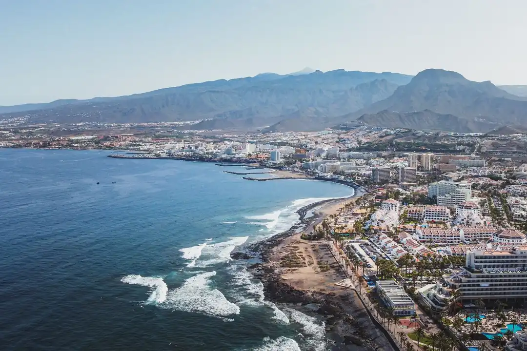 Vista aérea de la costa de Arona, en el sur de Tenerife, con hoteles junto al mar y montañas al fondo