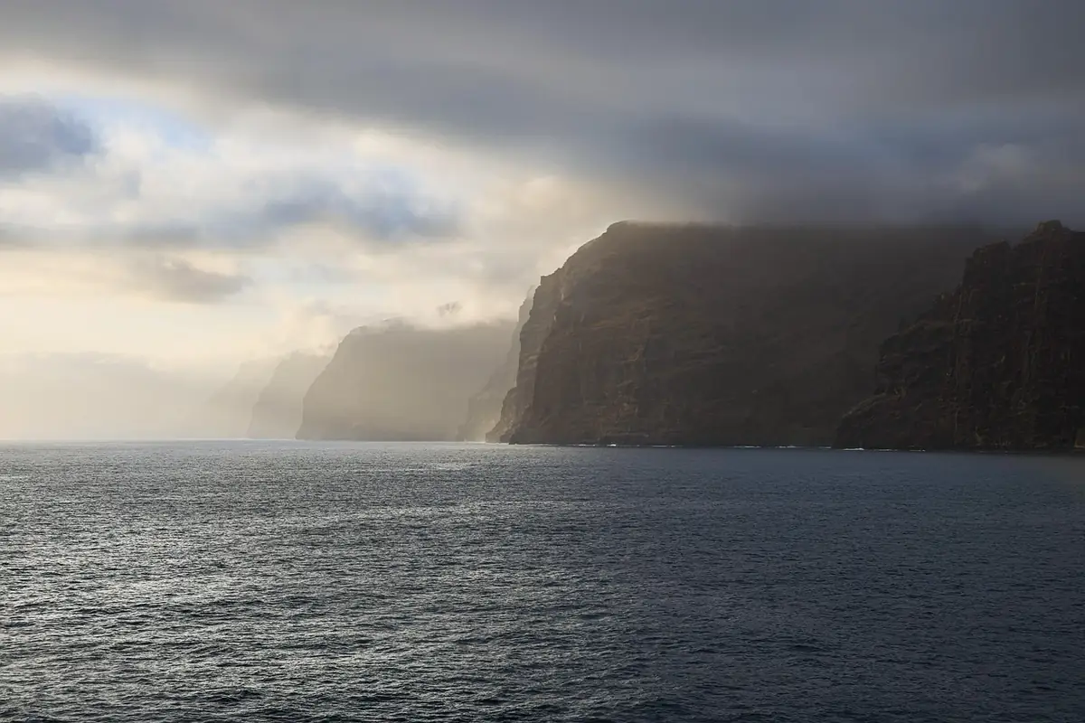 Acantilados de la costa de Tenerife entre la bruma, con el mar en calma