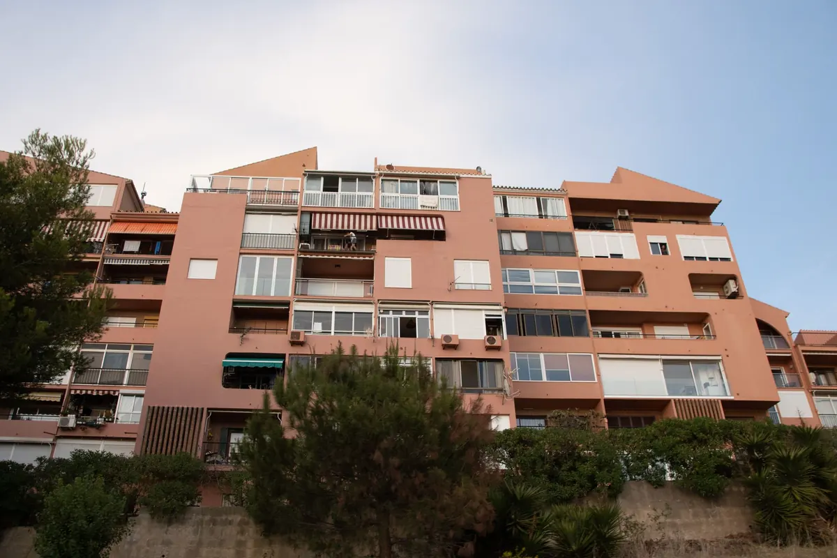 Edificio de apartamentos de varias plantas con balcones, toldos y unidades exteriores de aire acondicionado en la fachada
