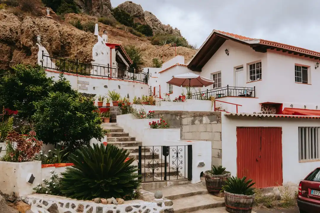 Casas blancas con terrazas y tejado de teja en un pueblo de Canarias, bajo un risco