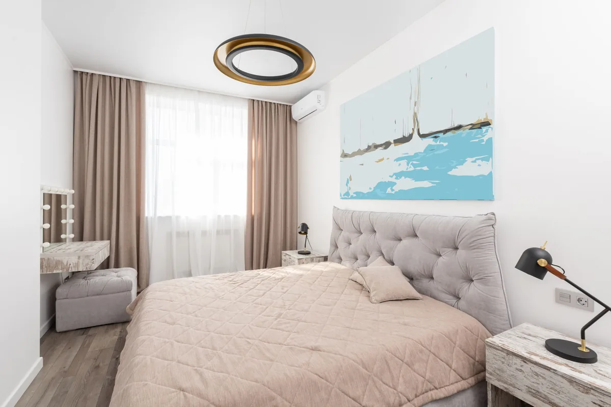Dormitorio con cama doble y un split blanco en la pared, junto a una ventana con cortinas