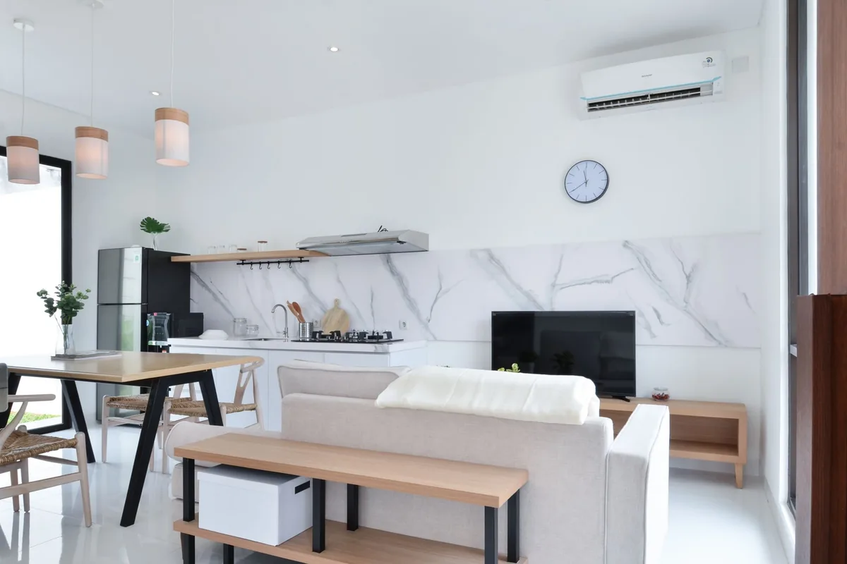 Salón comedor luminoso de paredes blancas con una unidad de aire acondicionado de pared