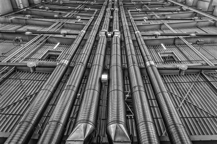 Red de conductos metálicos de ventilación recorriendo el techo de una instalación industrial