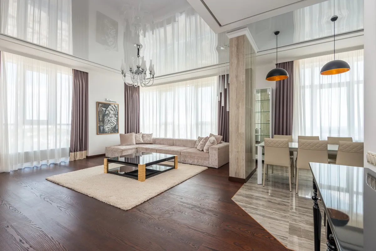 Salón amplio con techo blanco, cortinas claras y grandes ventanas