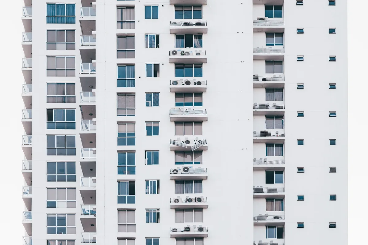 Fachada blanca de un edificio de apartamentos con las unidades exteriores de aire acondicionado en sus balcones