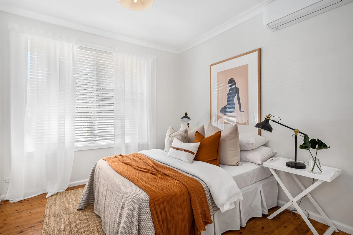 Dormitorio luminoso con cortinas blancas y un split de pared en lo alto