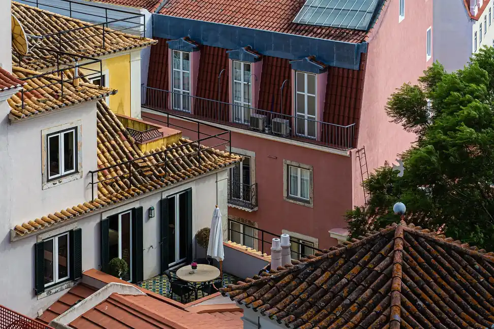Tejados de teja, terrazas y un balcón con dos unidades exteriores de aire acondicionado entre casas juntas, vistos desde arriba