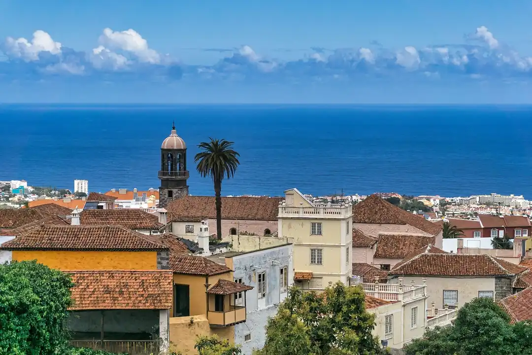 Tejados de teja, casas con balcones y un campanario de piedra en el casco de La Orotava, con el mar al fondo