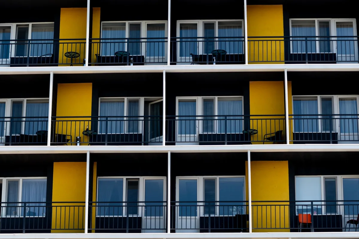 Fachada de un bloque de apartamentos con tres filas de balcones y paneles amarillos