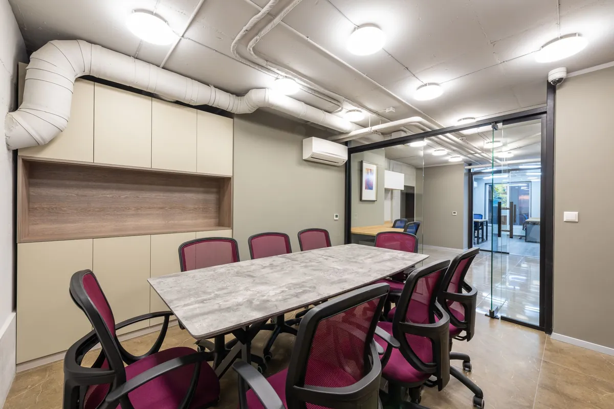 Sala de reuniones con un split en la pared y conductos de ventilación vistos en el techo