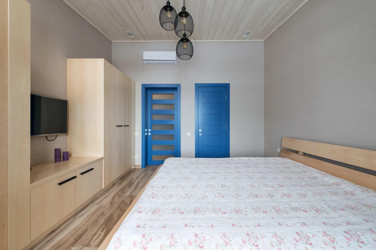 Dormitorio con un aire acondicionado de pared blanco sobre dos puertas azules
