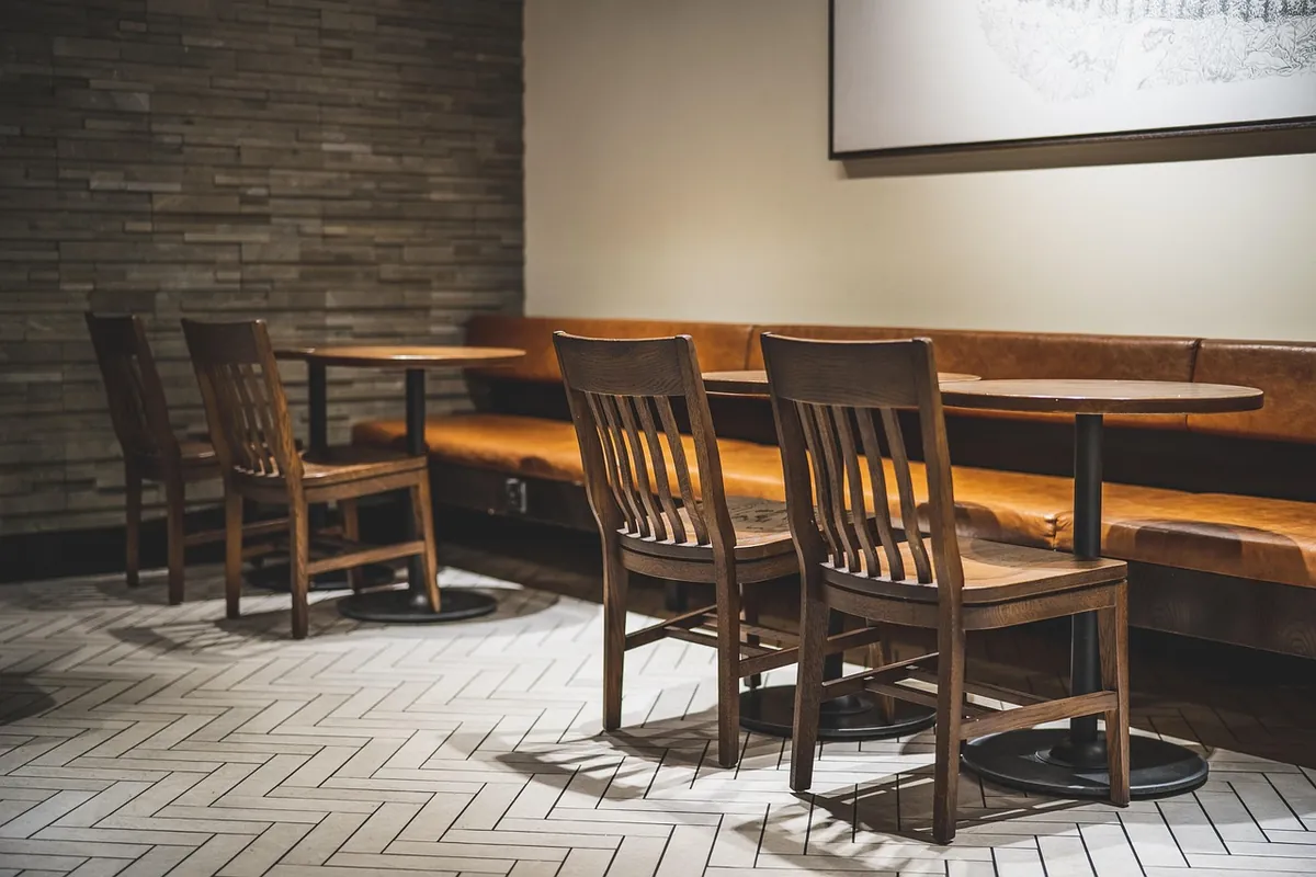Mesas y sillas de madera con un banco de cuero en una cafetería vacía
