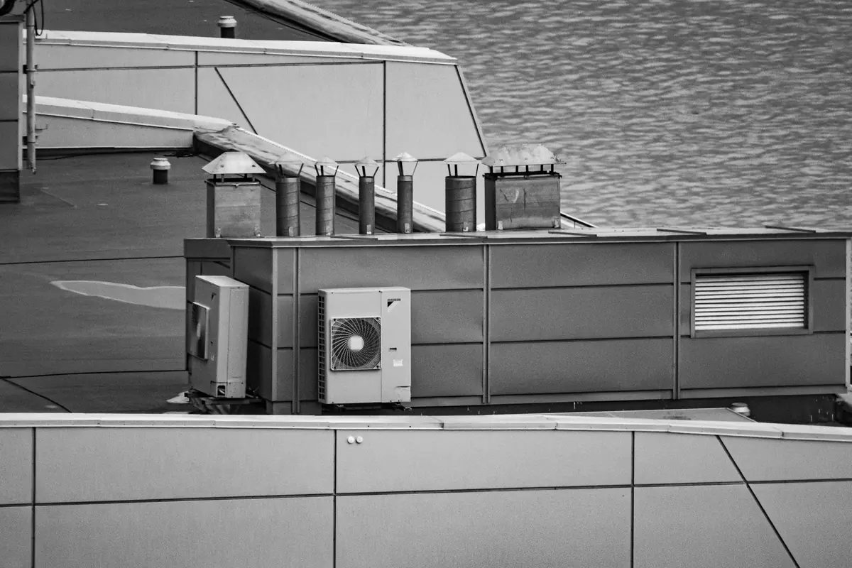 Unidades exteriores de aire acondicionado sobre una azotea plana, junto al agua, en blanco y negro