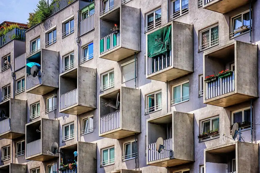 Fachada de un bloque de pisos con balcones de hormigón y barandillas blancas