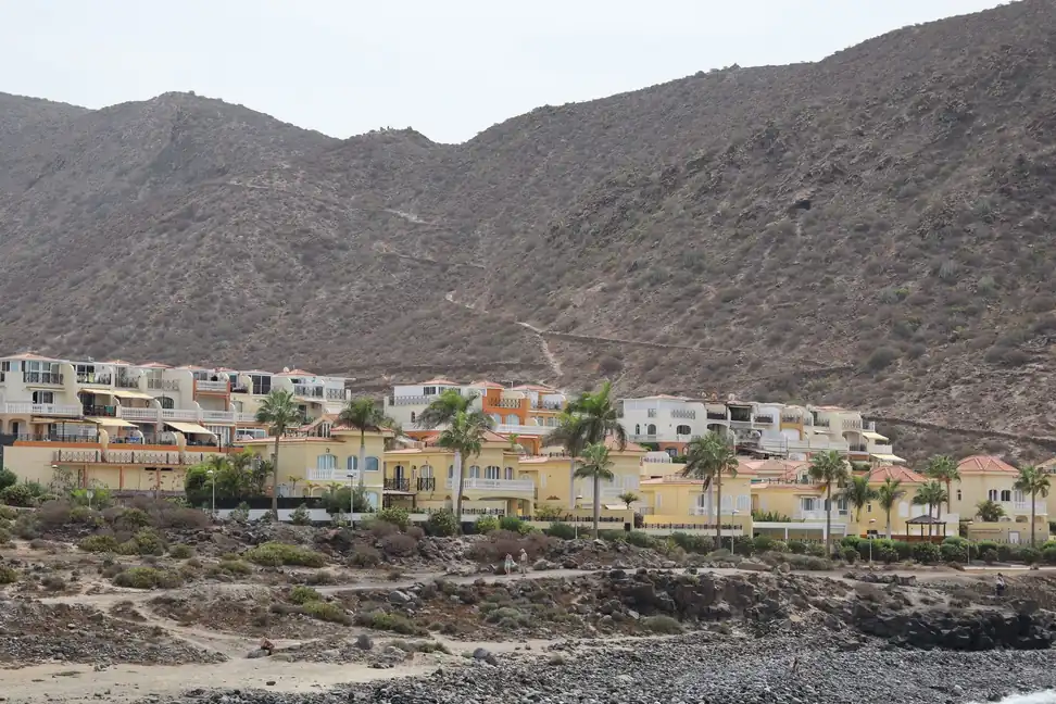 Urbanización de casas con terrazas en una ladera seca de Tenerife, junto a la costa rocosa
