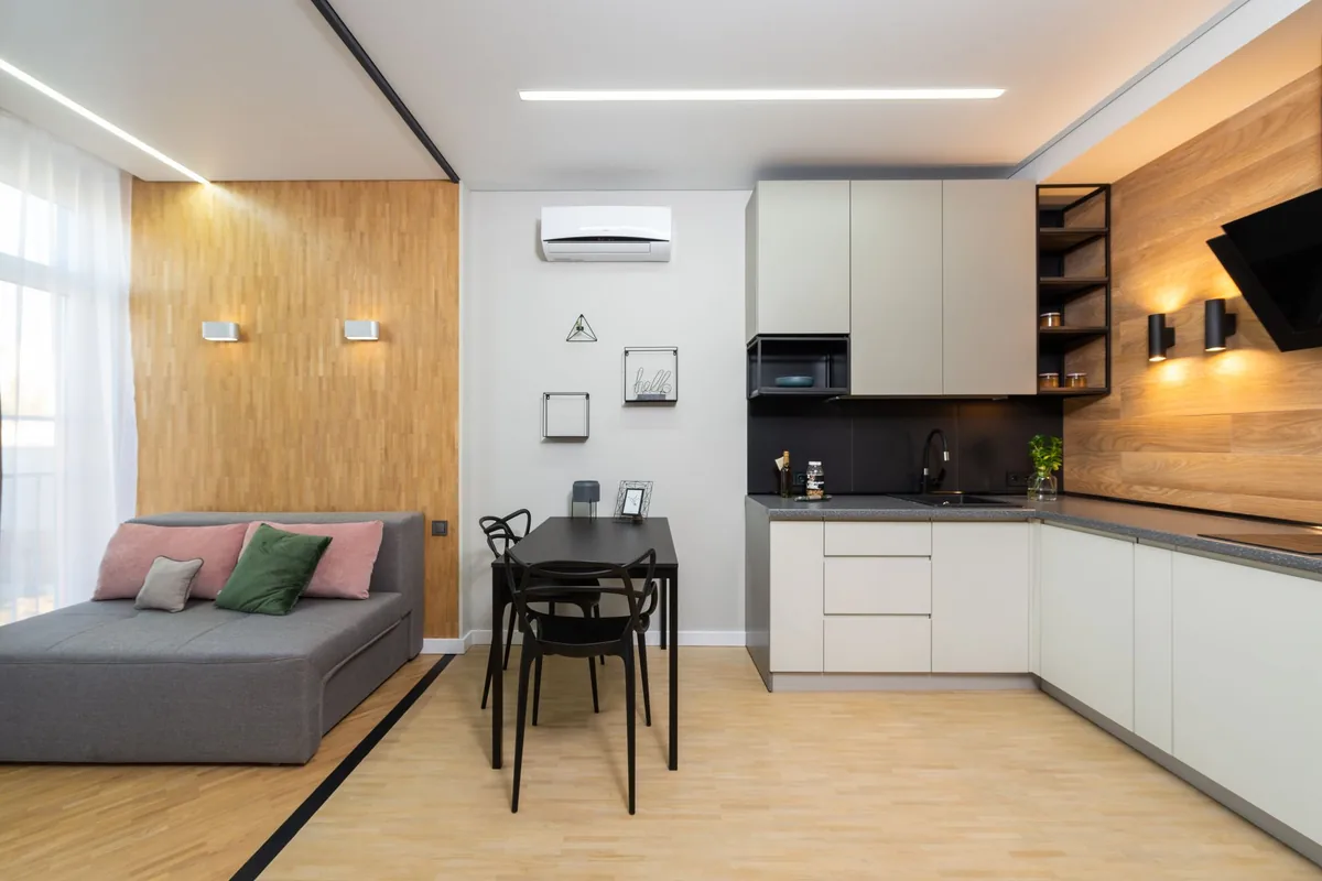 Apartamento estudio con sofá cama, mesa y cocina, y un split de pared sobre la mesa