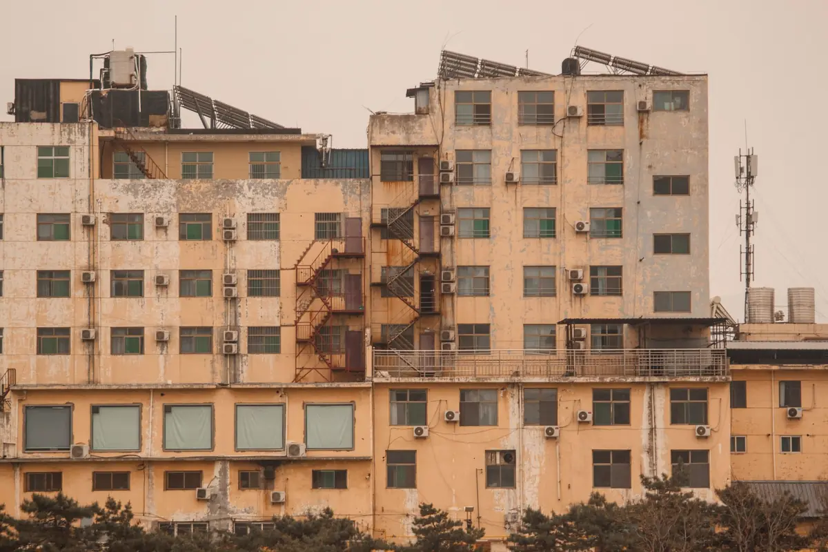 Edificios con muchas unidades exteriores de aire acondicionado en la fachada, bajo un cielo amarillento