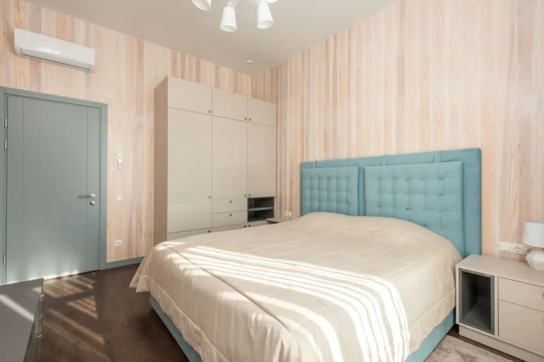 Split de aire acondicionado blanco instalado en lo alto de la pared de un dormitorio luminoso