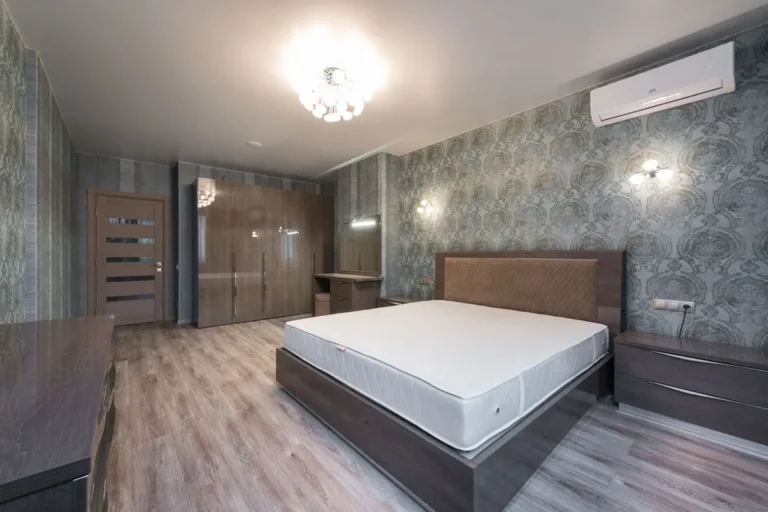 Split de aire acondicionado instalado sobre la mesilla de un dormitorio con papel pintado